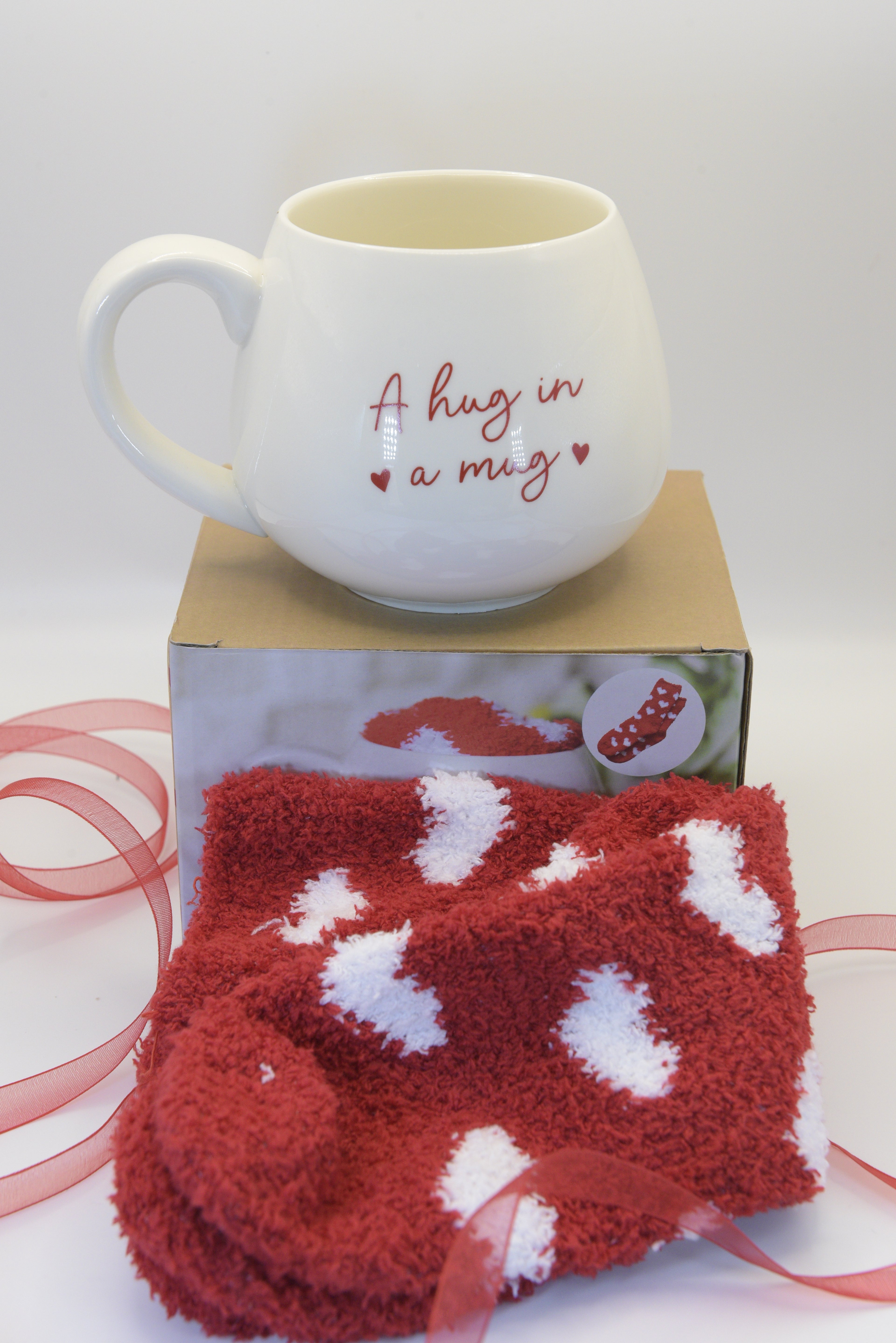 Send a warm hug from afar with our charming 'Hug in a Mug' gift set. This delightful pairing features a heart-adorned mug and cosy socks—the perfect combination for comfort and care. 
