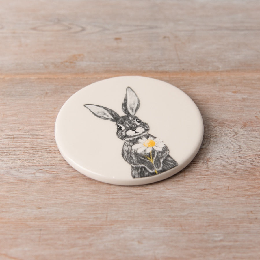 White ceramic coaster with hare holding daisy sketch, matches hare jug